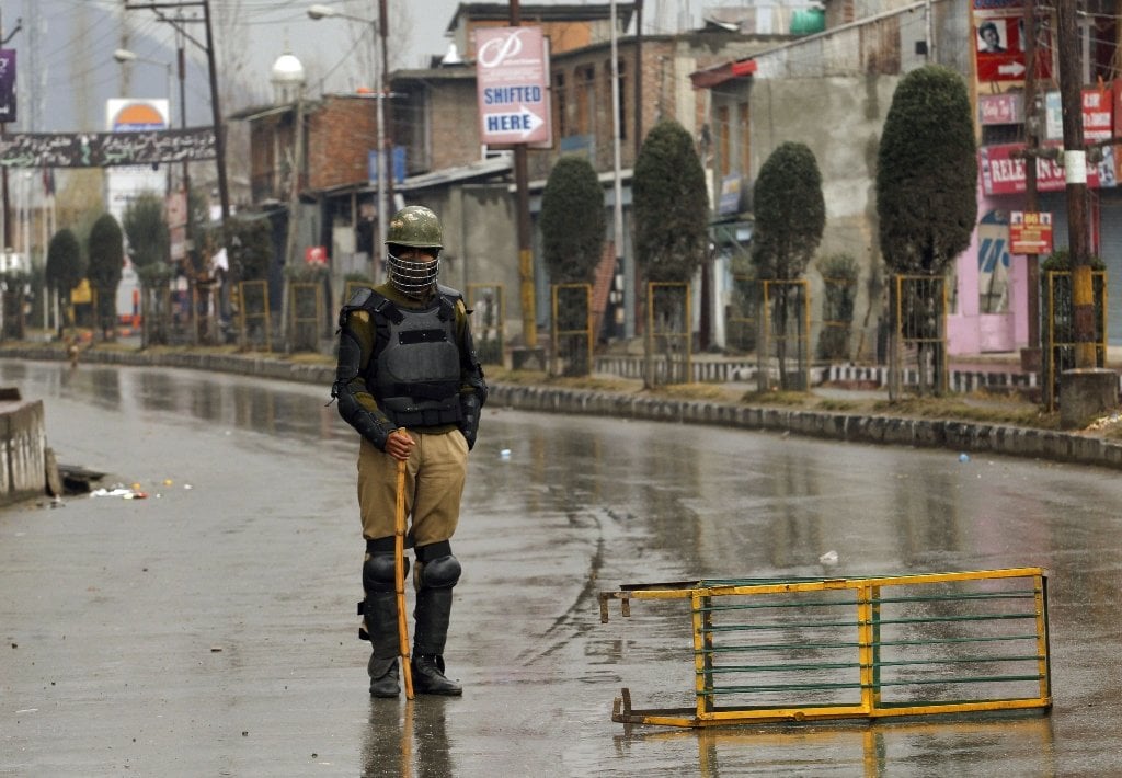 indian policeman wearing riot gear stands guard at a barricade setup in india photo reuters