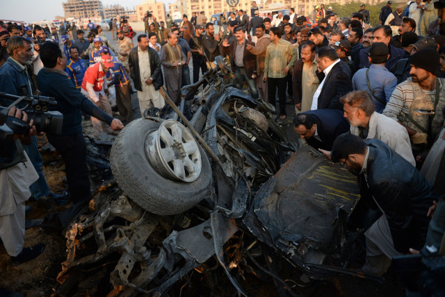 pakistani security officials examine the wreckage of a destroyed vehicle at the site of the suicide bombing in karachi on january 9 2014 photo afp pakistani security officials examine the wreckage of a destroyed vehicle at the site of the suicide bombing in karachi on january 9 2014 photo afp