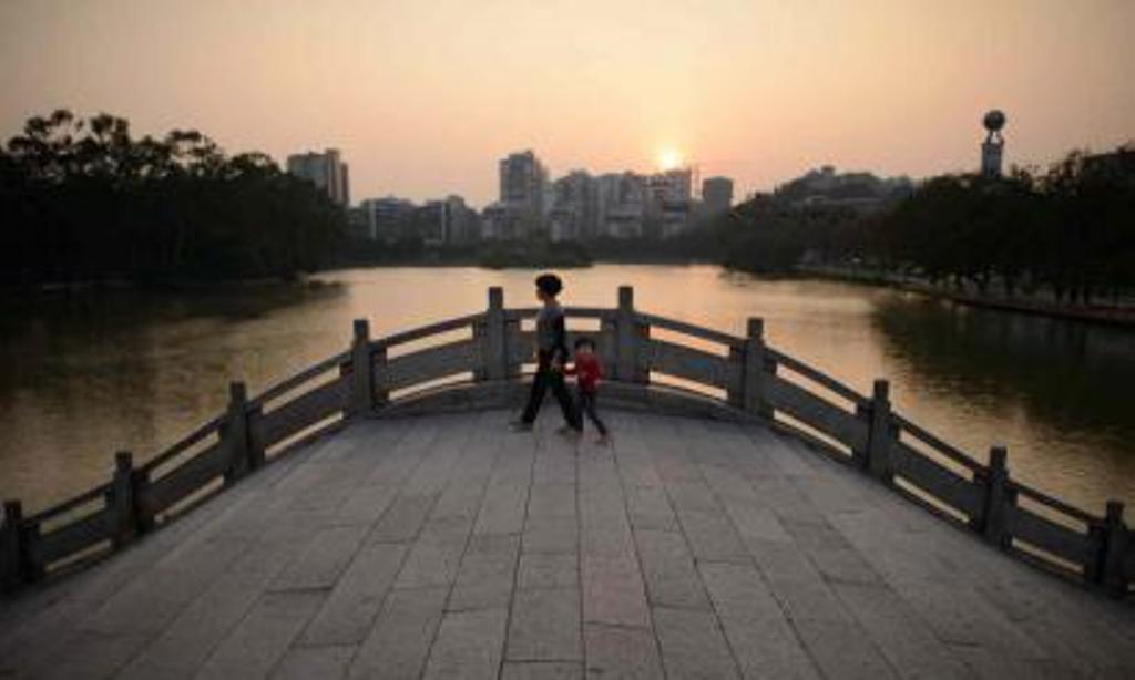 a woman and a child walking across a bridge in a park in fuzhou the capital of china 039 s south eastern fujian province photo afp