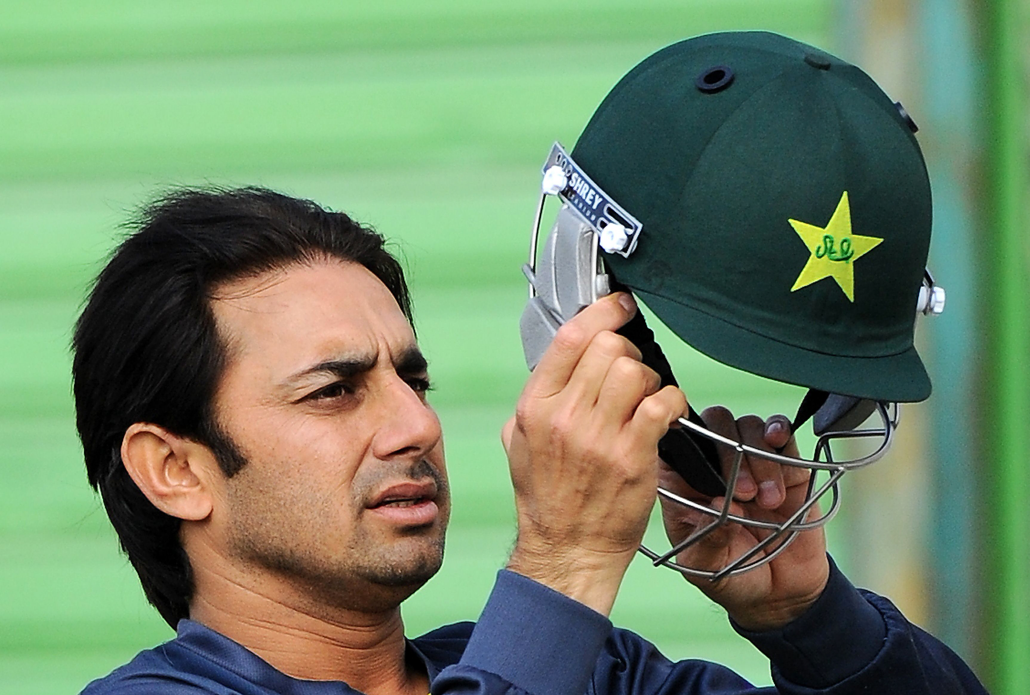 saeed ajmal puts on his helmet during a practice session at the sharjah international cricket stadium photo afp