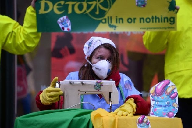 greenpeace activists pretend they are sewing contaminated clothes with chemicals represented by little monsters during a protest stunt photo afp