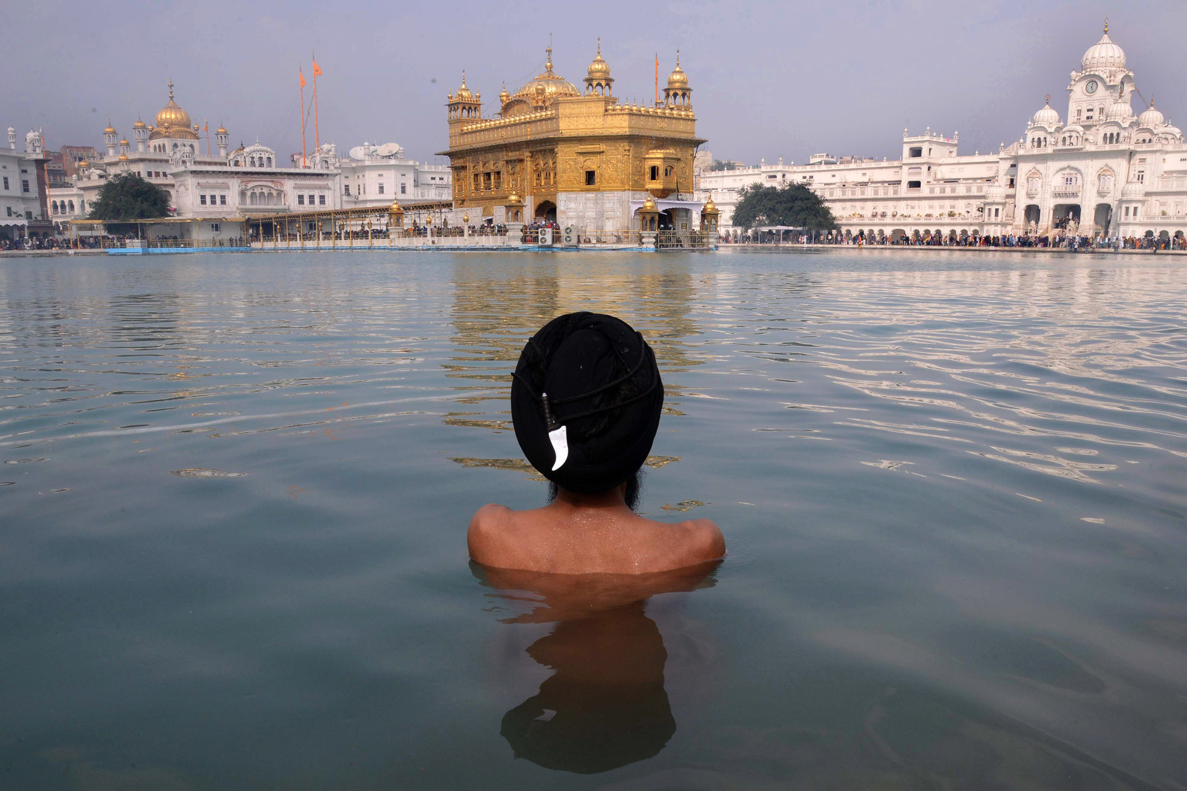 an indian sikh devotee takes a dip in the holy sarover water tank during the maghi mela at the sikh shrine golden temple in amritsar on january 14 2014 photo afp