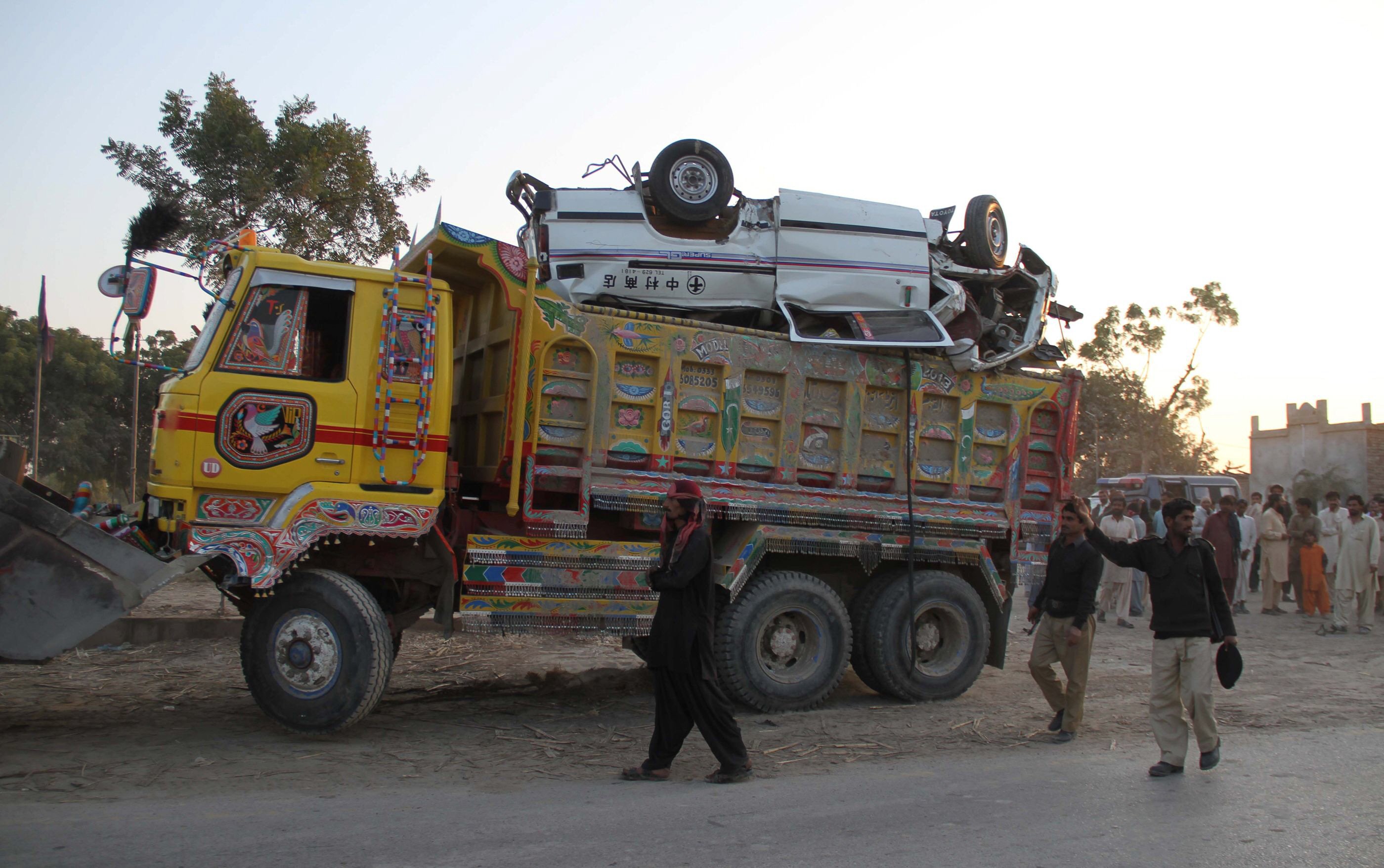 policemen remove a dump truck and a school van from a crash site after an accident near the town of nawabshah some 270 kilometres north of karachi on january 15 2014 photo afp