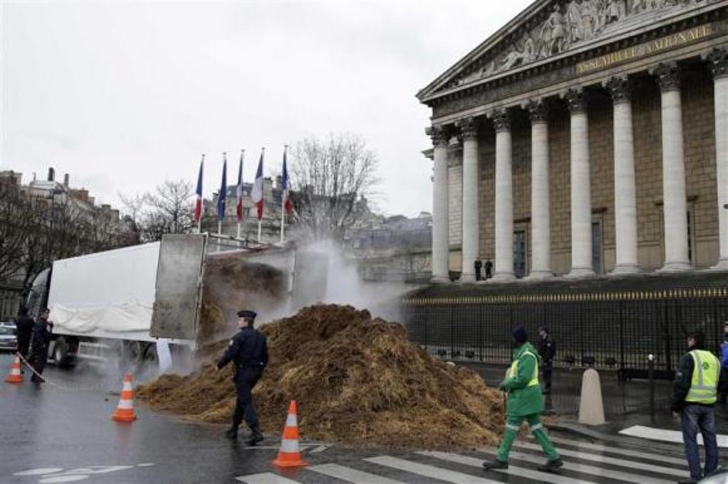 french police and municipal workers walk near a large pile of manure sitting in front of the national assembly in paris january 16 2014 photo reuters