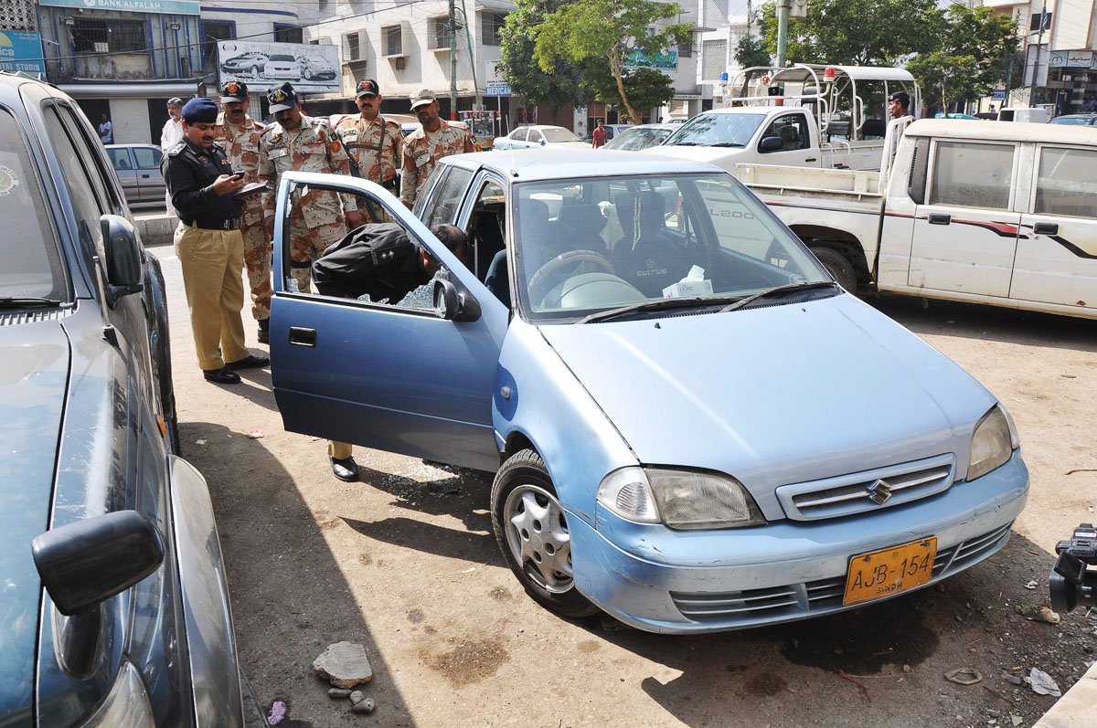 police and rangers officials inspect the car of a plastic surgeon who was gunned down near tariq road on monday photo mohammad azeem experss file