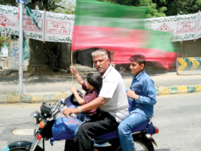 a man drives a motorcycle as two children sit on the bike along with him the man is without a helmet and doesn t have his eyes on the road photo file