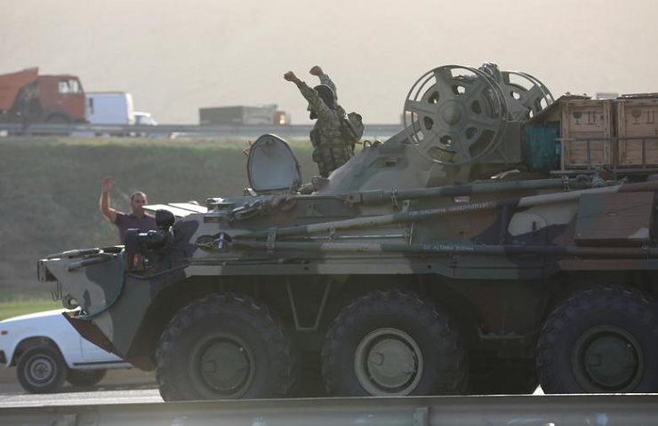 An Azerbaijani service member drives an armored carrier and greets people gathered on the roadside in Baku, Azerbaijan, September 27. PHOTO: REUTERS