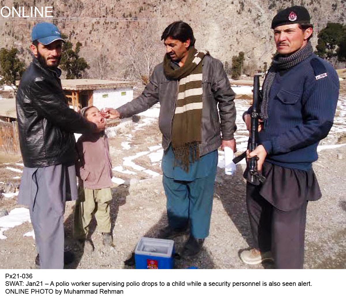 a health worker administers polio drops to a child in swat as an armed security personnel keeps watch photo online