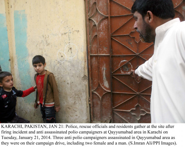 an official points to wards a bullet hole caused by the firing on polio workers in karachi on tuesday as two children look on photo ppi