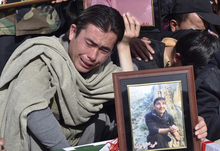 a man holds picture of his relative a victim of mastung bomb attack on a bus beside the covered body during a funeral in quetta january 24 2014 photo reuters