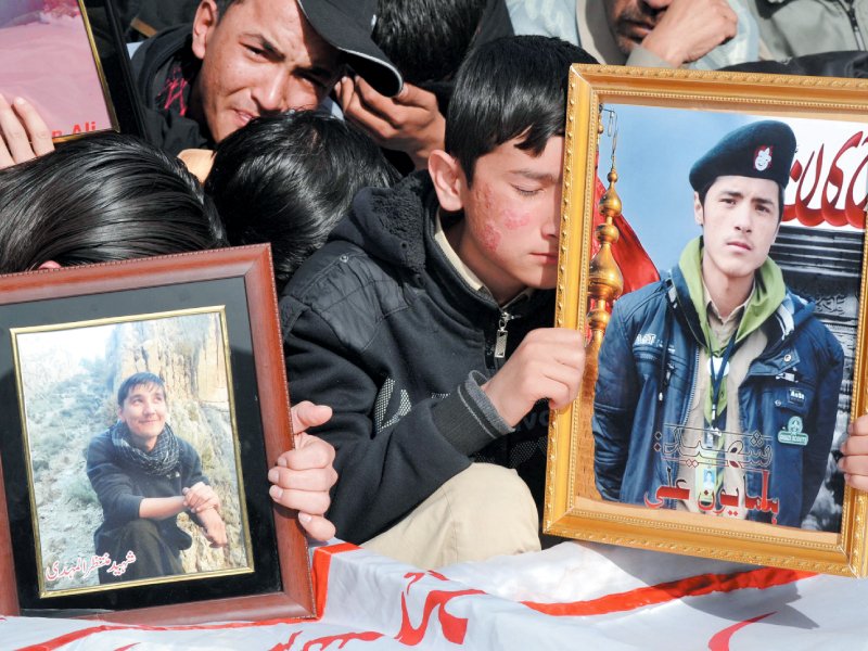 families hold pictures of their loved ones during the funeral of blast victims photo reuters