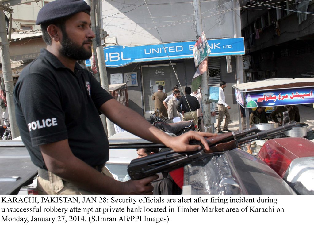 police official stands alert after a group of robbers stole rs275 000 from timber market branch of united bank limited ubl on monday morning photo ppi