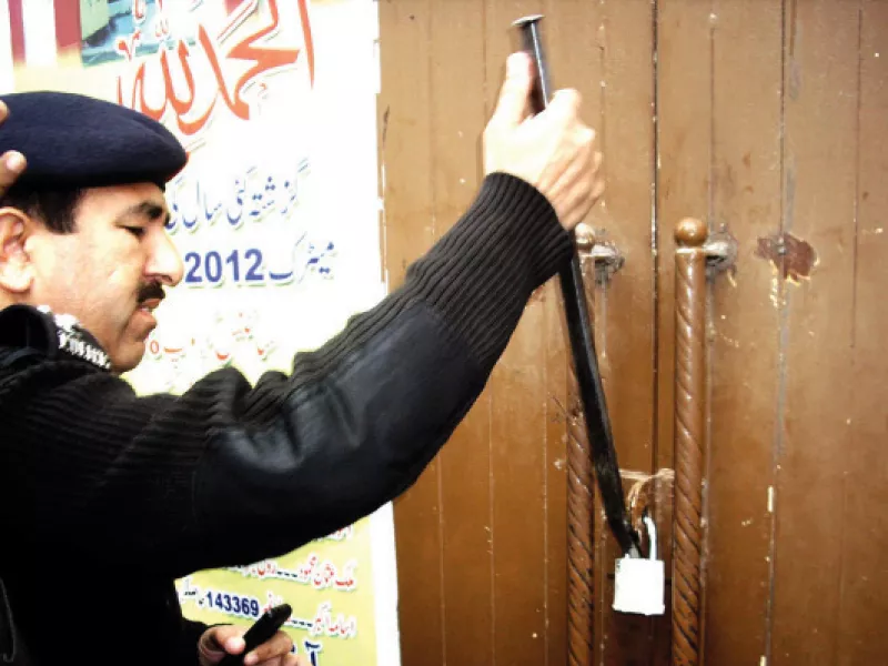 a police official is breaking the lock of the school photo file a police official is breaking the lock of the school photo file