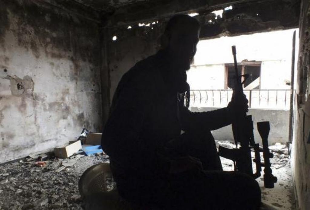 a free syrian fighter holds his weapon inside a damaged building in the besieged area of homs photo reuters