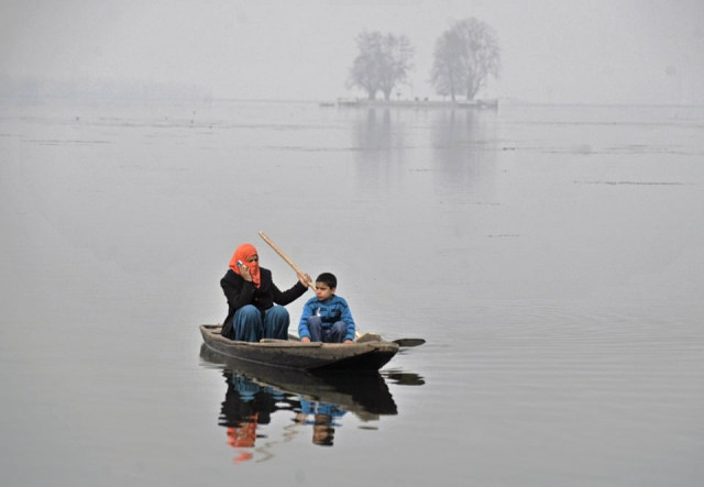 kashmiri woman speaks on a mobile phone as she sails a shikara on a srinagar 039 s dal lake on january 2 2011 photo afp