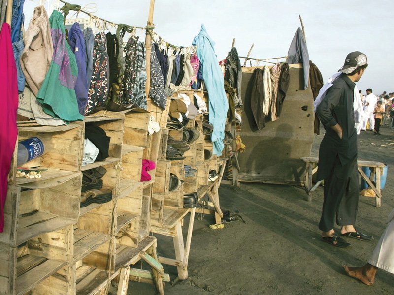 bustling with activity this strip of clifton beach opposite bilawal house is a popular getaway for these people each sunday a stall rents out swimming trunks and also holds shoes in the custom made shoe racks photos express