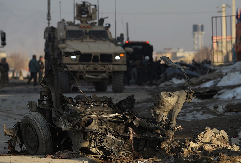 afghan security forces stand guard near the wreckage of a car which was used in a bomb attack in the pol e charkhi area of kabul on february 10 2014 photo afp