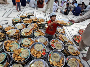 a pakistani boy distributes plates of food donated to worshippers to break their fast on the first day of the holy fasting month of ramazan in a mosque in karachi photo ap