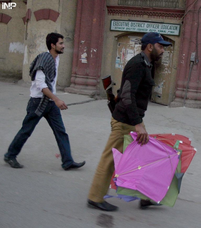 a policeman carrying kites he confiscated from a youngster in rawalpindi photo inp