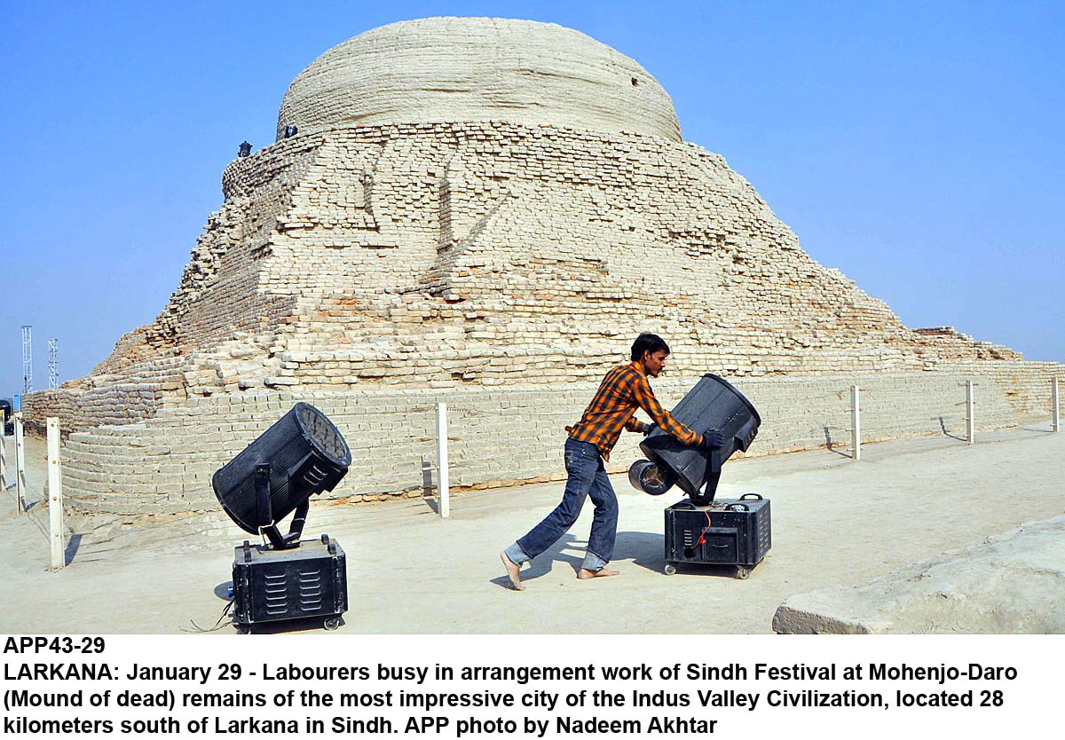 workers move heavy lights near the stupa of moenjo daro a world heritage site with metal pylons for the upcoming sindh festival visible in the background photo app