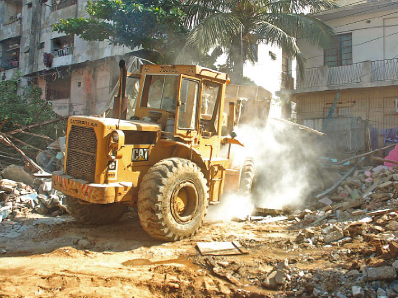 a bulldozer crushes illegal constructions in karachi a 1 500 square yard plot in gulistan e jauhar was clearly marked as a park in the neighbourhood s master plan but nearly five years ago some residents built houses over the land photo file