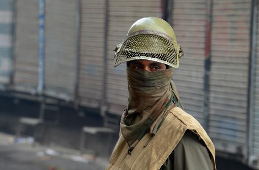 an indian policeman stands guard in front of closed shops in srinagar on february 11 2014 photo afp