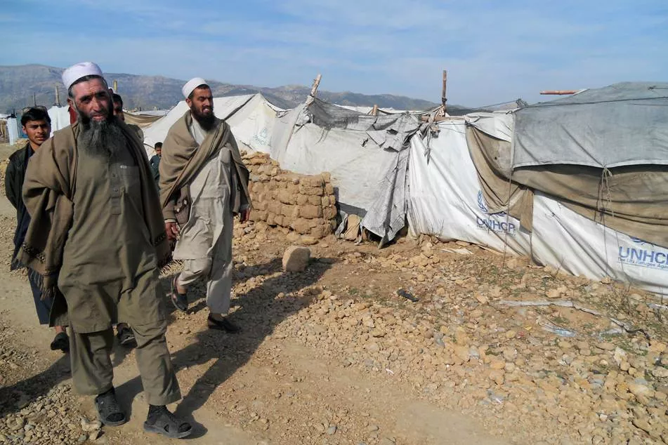 tribesmen walk past shelters at the unhcr internally displaced people camp in togh sarai in the tribal district of hangu on february 13 2014 photo afp tribesmen walk past shelters at the unhcr internally displaced people camp in togh sarai in the tribal district of hangu on february 13 2014 photo afp