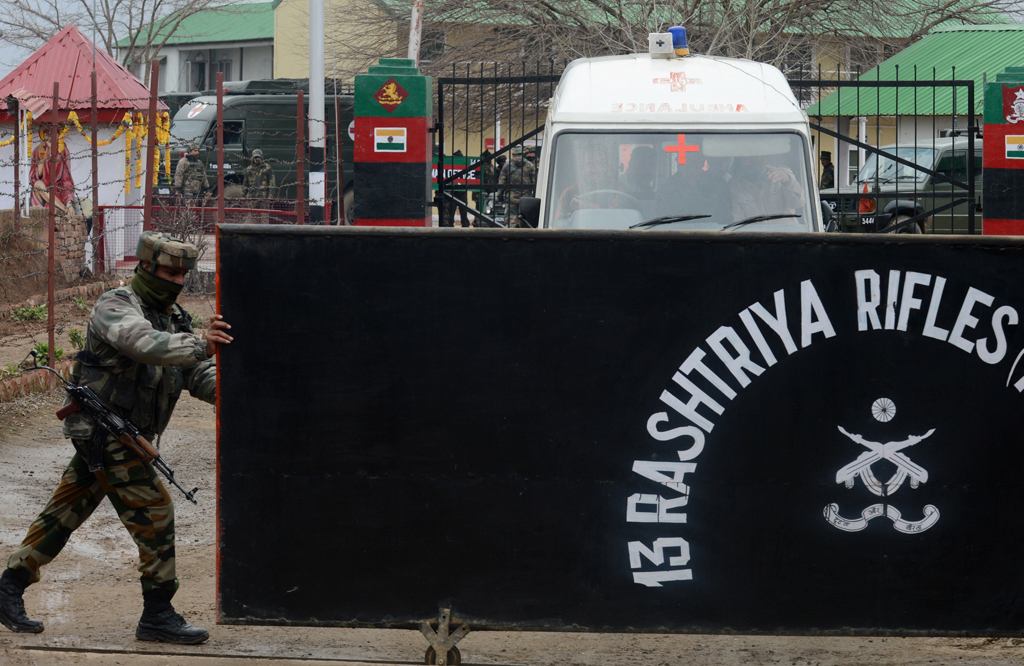 an indian army soldier opens the gates of the rashtriya rifles camp for a team of medics leaving after conducting post mortems on the bodies of five soldiers killed at an army camp at safapora some 20 kms 12 miles from srinagar on february 27 2014 photo afp