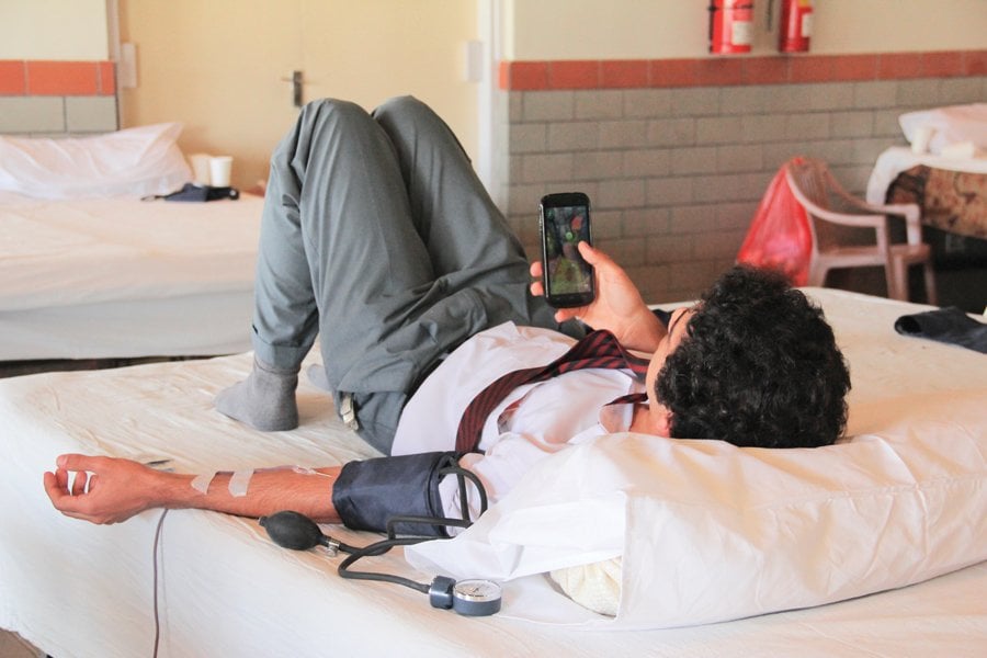 a student of the karachi grammar school playing on his mobile phone while donating blood at the school s blood donation camp on thursday photo ayesha mir express