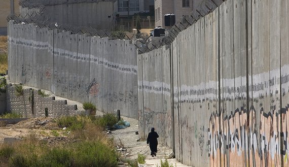 a palestinian woman walks along the controversial israeli barrier in al ram in the west bank on the outskirts of jerusalem in 2010 photo reuters