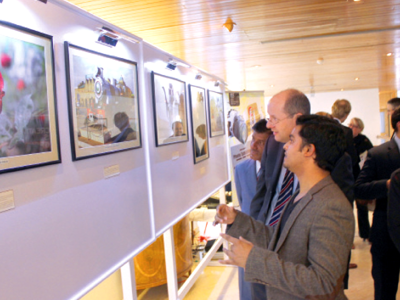 an amateur photographer briefs british high commissioner philip barton about the photographs photo express