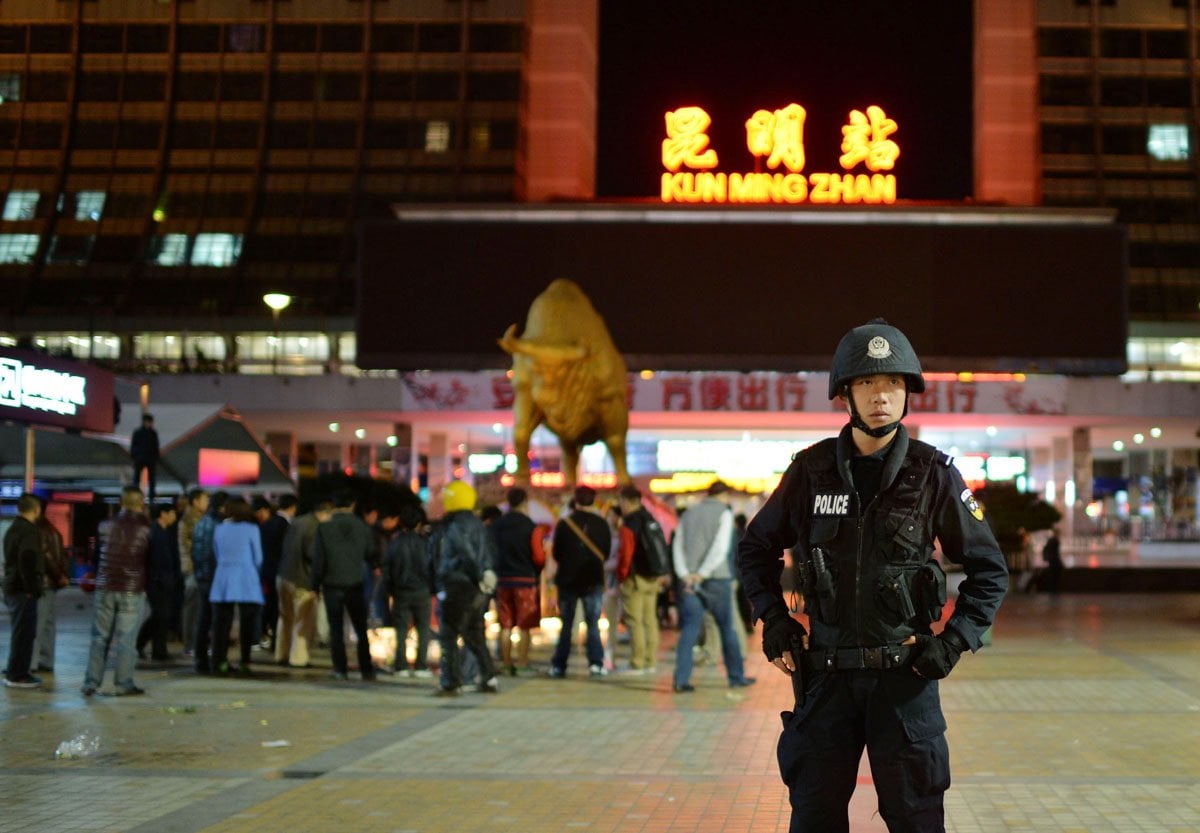 a policeman r stand guarding as chinese mourners light candles at the scene of the terror attack at the main train station in kunming southwest china 039 s yunnan province photo afp