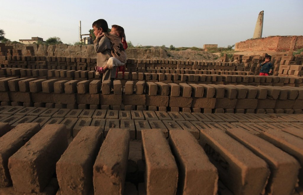 a boy carries his sibling as he walks past bricks left to dry at a kiln photo reuters