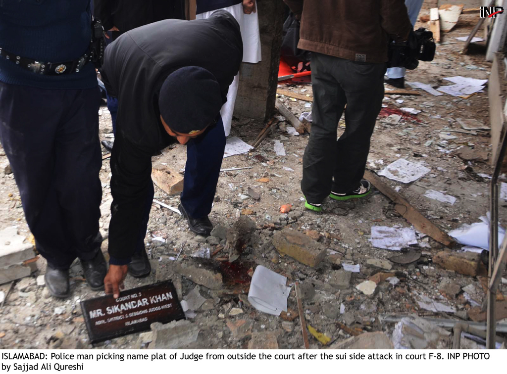 a police man picking up the name plate of a judge from the ground after the suicide attack at district and session court in islamabad on monday march 3 2014 photo inp