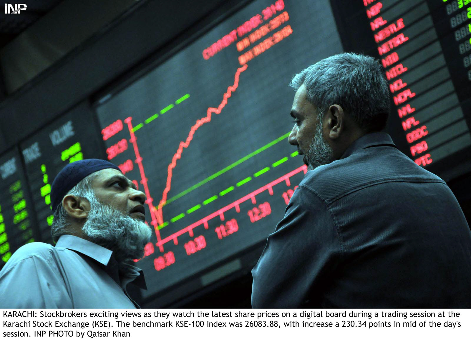 two stock brokers exchange views with the stock exchange electronic board in the background photo inp