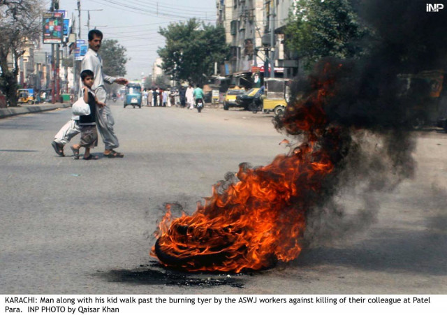 a man crosses a street along with his son as a tyre set alight by protesters burns in patel para photo inp a man crosses a street along with his son as a tyre set alight by protesters burns in patel para photo inp