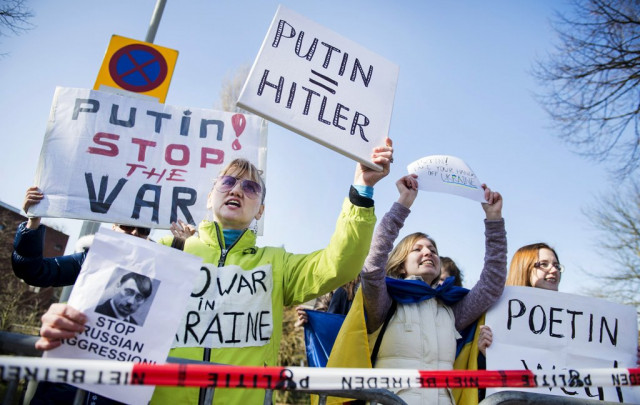 demonstrators holding placards against the russian president stage a protest outside the russian embassy in the hague on march 5 2014 to protest against the presence of russian troops on the ukrainian peninsula of crimea photo afp