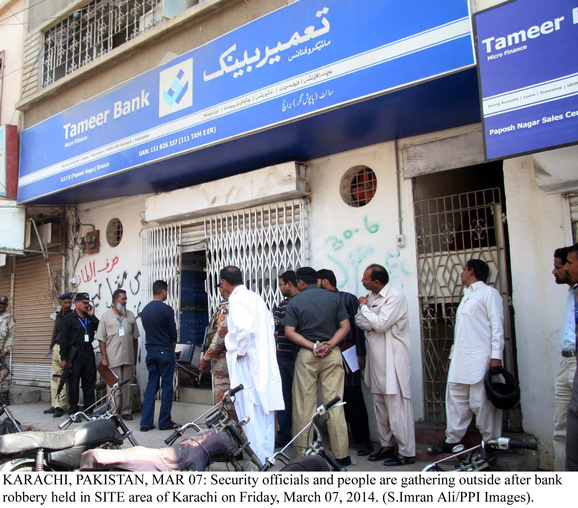 security and bank officials gather outside the tameer bank which was burgled on friday photo ppi