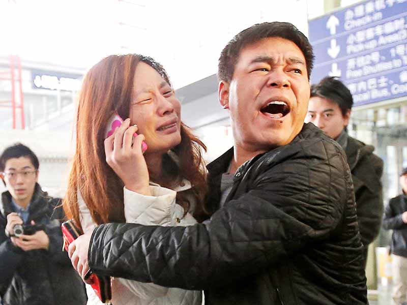 a relative of a passenger onboard malaysia airlines flight mh370 cries as she talks on her mobile phone at the beijing airport in beijing photo reuters