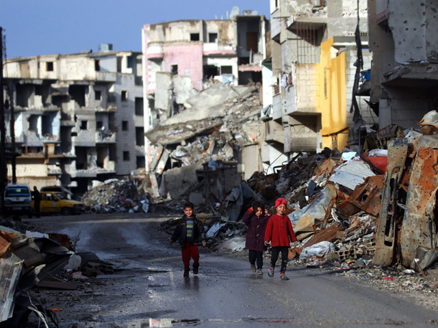 syrian children walk along a destroyed street in raqqa the former de facto capital of the islamic state is group on february 18 2018 photo afp