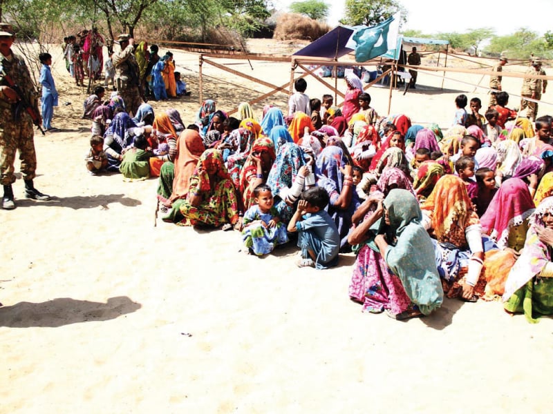 women wait for their turn to get relief goods at an army camp in tharparkar photo online