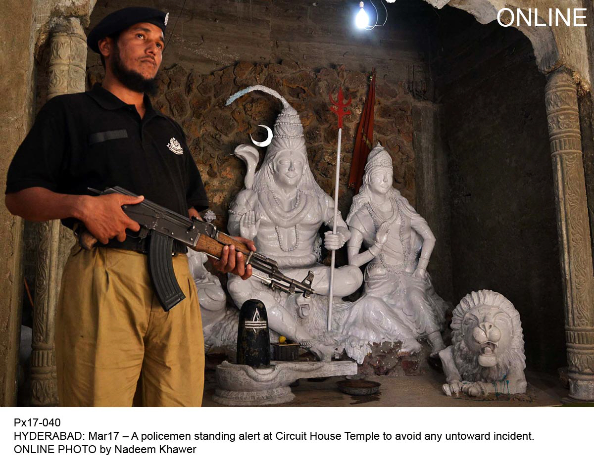 a police official stands guard outside a temple in hyderabad after fears of reprisal attacks following riots in larkana on sunday photo online