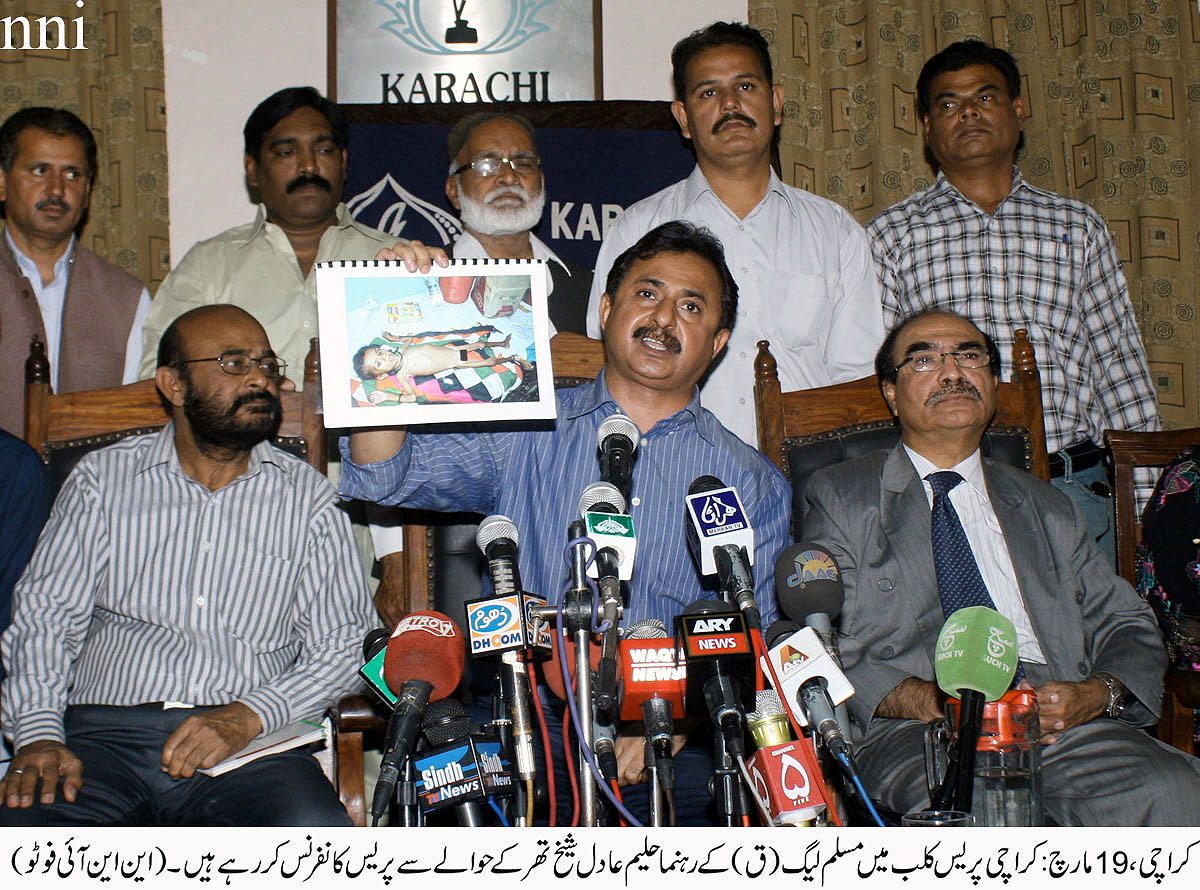 pml q 039 s haleem adil shaikh holds up a picture of a severely malnourished thari child during a press conference at the karachi press club on wednesday photo nni