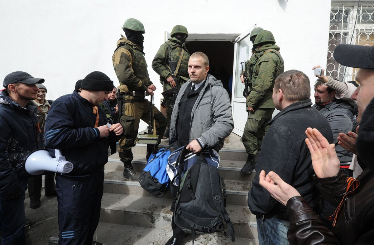 an ukrainian officer leaves his barracks as russian soldiers patrol at the ukrainian navy headquarters in the crimean city of sevastopol on march 19 2014 photo afp