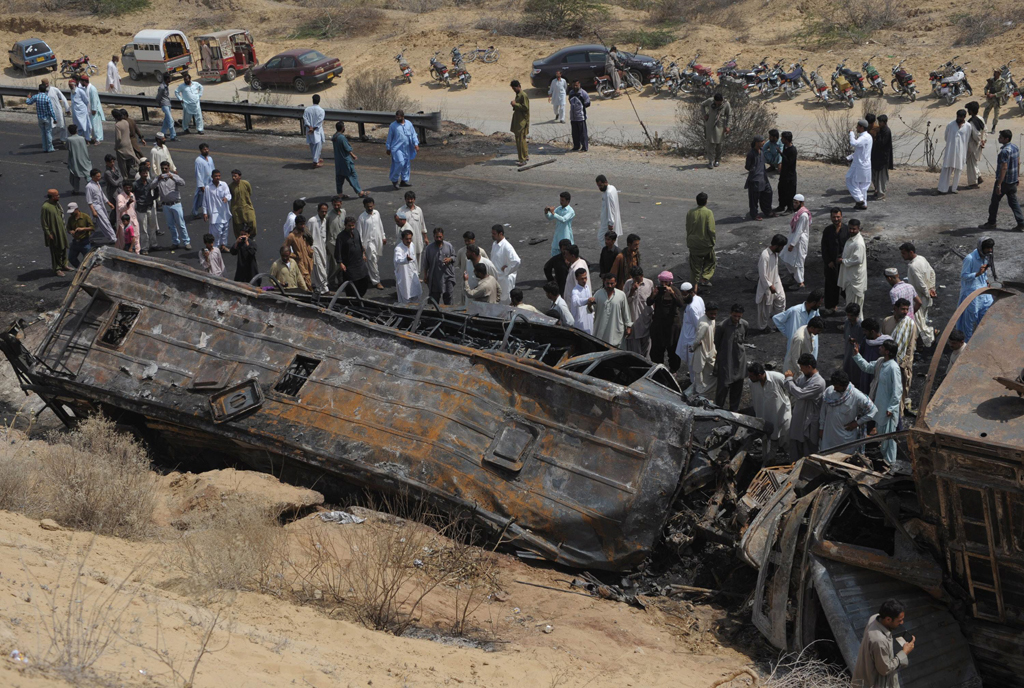 onlookers gather near the burnt wreckage of a passenger bus in hub near gadani on march 22 2014 photo afp