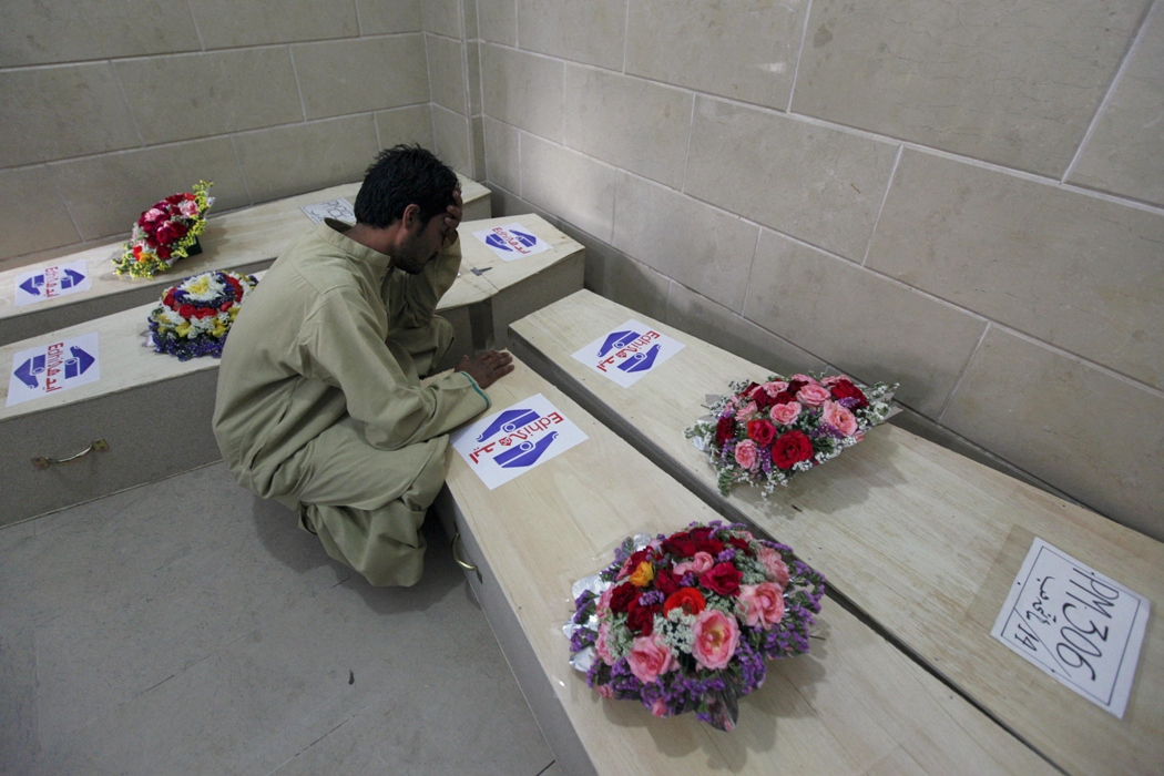 abdul jabbar who has yet to identify the body of his deceased brother jalal jan grieves over coffins of the victims of the hub road accident before their burial in edhi morgue in karachi march 24 2014 reuters