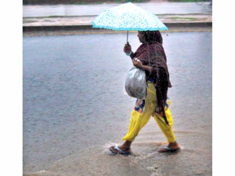 a woman splashes through rainwater accumulated on ijp road on monday photo muhammad javaid express