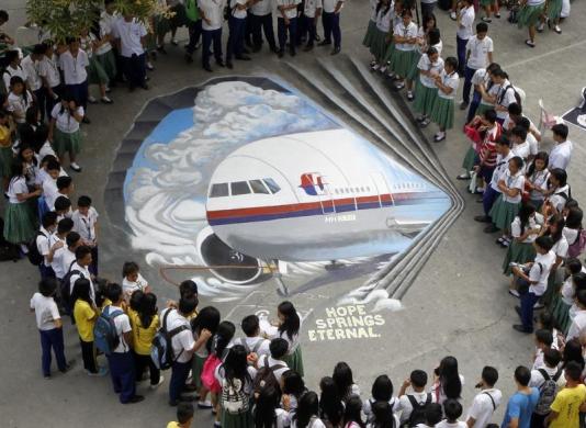 students gather around a three dimensional artwork based on the malaysia airlines flight mh370 that was painted on a school ground in makati city philippines march 17 2014 photo reuters