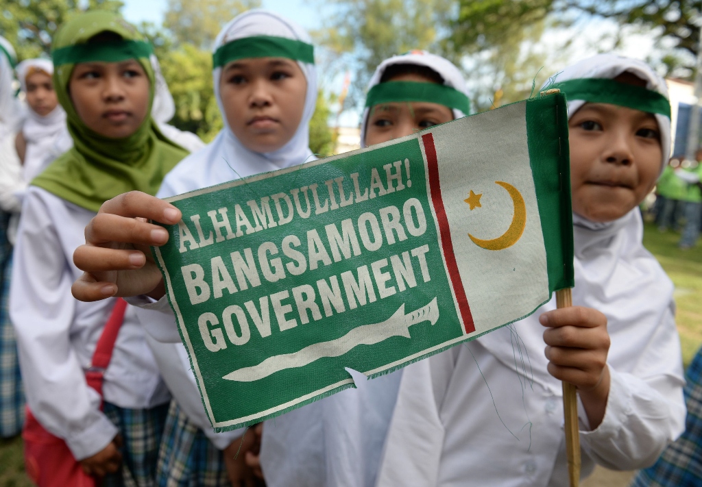 young muslims hold a moro islamic liberation front milf miniature flag as they gather for a rally in support of the peace agreement with the government in cotabato city on the southern island of mindanao on march 27 2014 photo afp