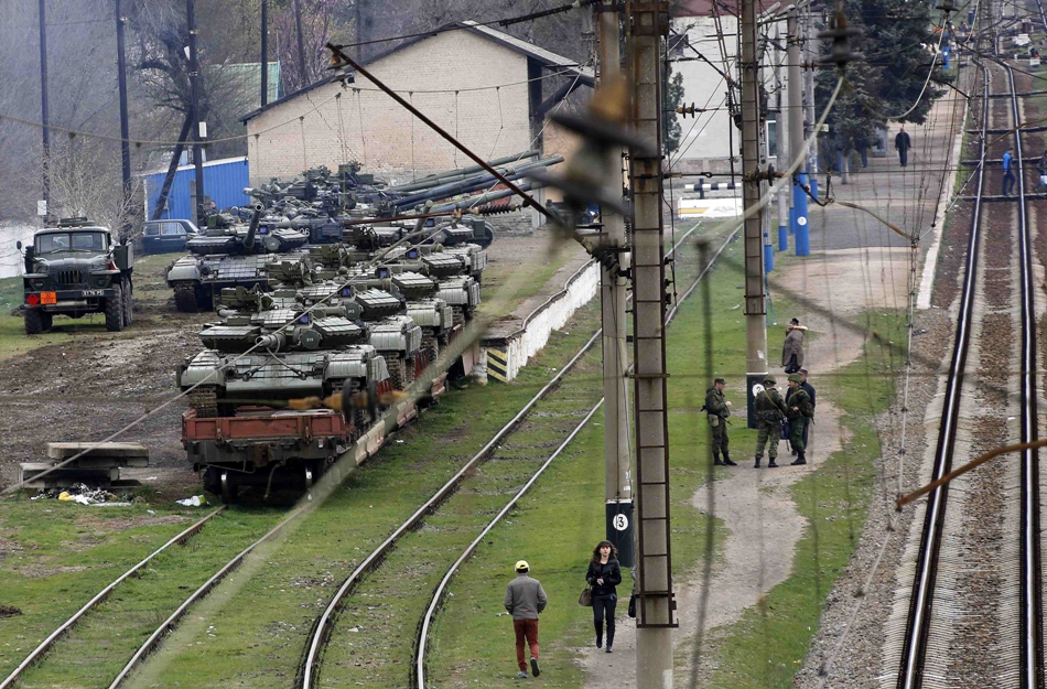 russian soldiers r and local civilians are seen at a train station where ukrainian tanks are being loaded onto a train in northern crimea on thursday photo reuters